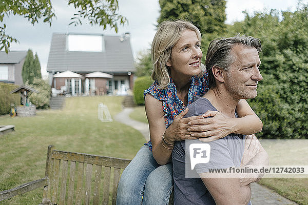 Smiling mature couple embracing in garden of their home