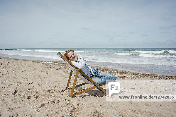 Smiling woman lying in deck chair  enjoying sunbath at the beach