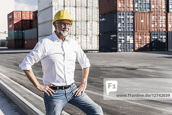 Businessman at cargo harbour  wearing safety helmet  portrait