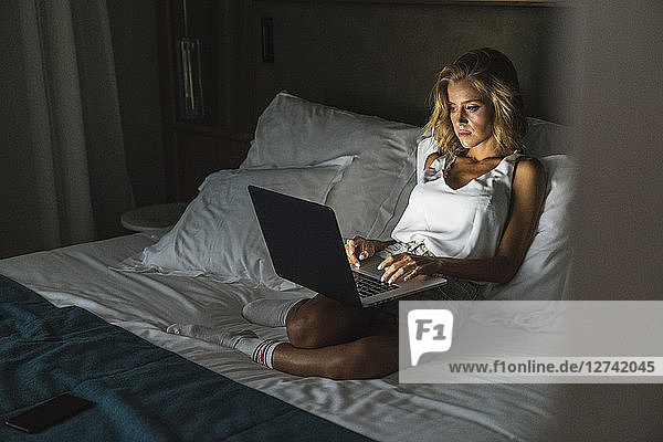 Woman sitting on bed  using laptop