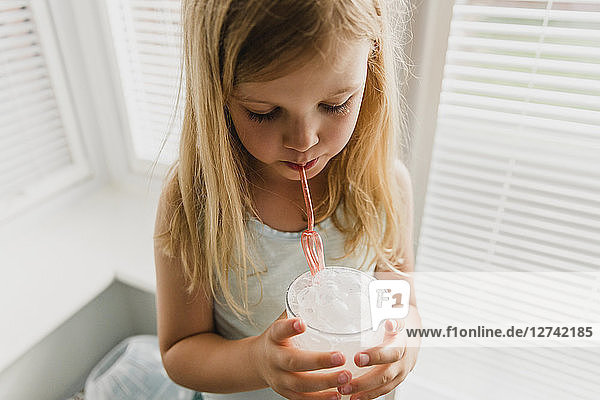 Blond little girl blowing milk bubbles