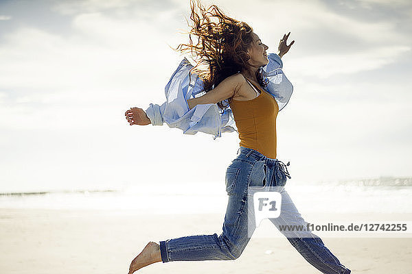 Happy woman having fun at the beach  jumping in the air