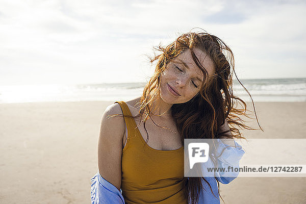 Portrait of a redheaded woman on the beach  with eyes closed