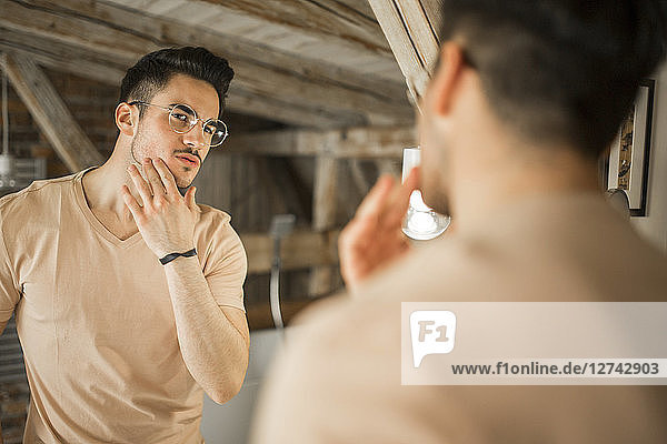 Young man looking in bathroom mirror