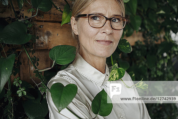 Portrait of businesswoman at wall with climbing plants