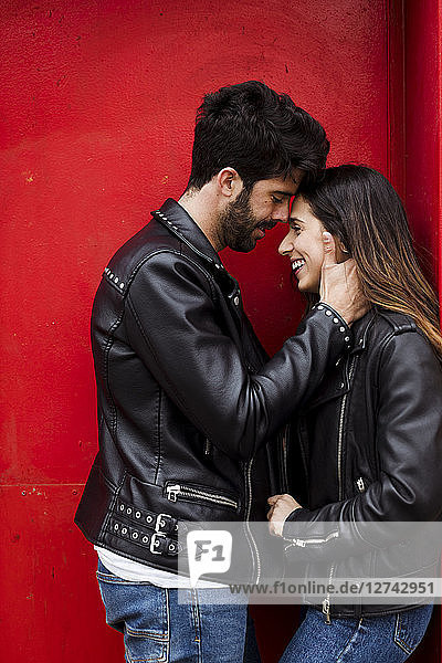 Affectionate happy young couple standing at red door