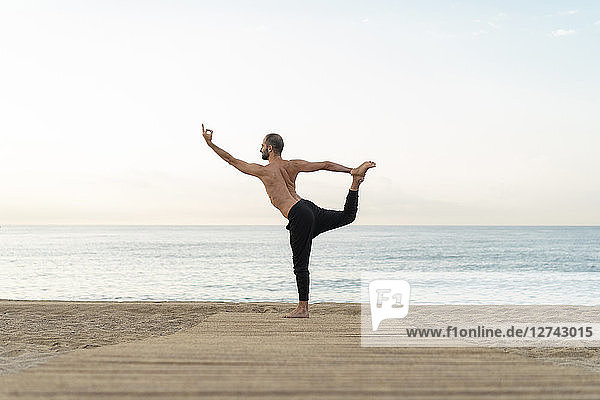 Spain. Man doing yoga on the beach in the evening  dancer position