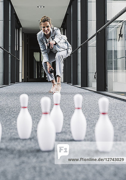 Smiling businessman bowling in office passageway