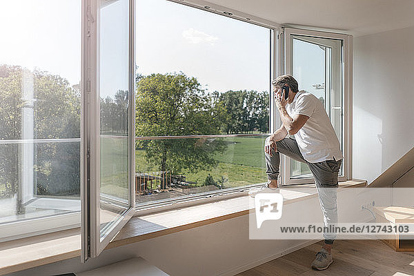 Mature man on the phone at the window in empty room