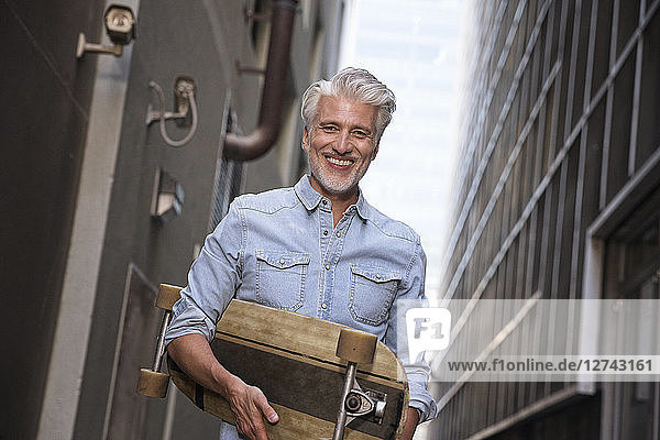 Mature man with longboard in an alley