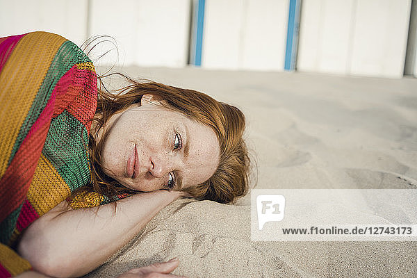 Redheaded woman resting in sand on the beach