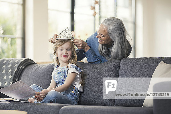 Grandmother playing with granddaughter  puuting crown on her head