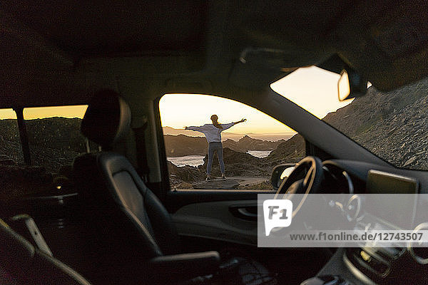 Young woman enjoying sunset at the beach  view through car