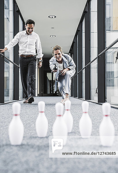 Happy businessman and businessman bowling in office passageway