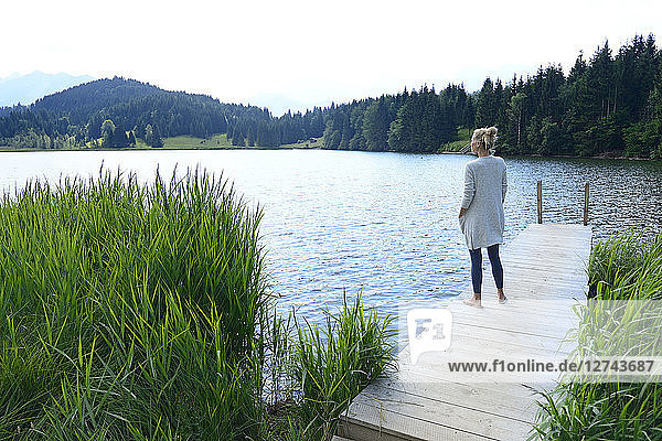 Germany Mittenwald woman standing on jetty at lake looking at distance