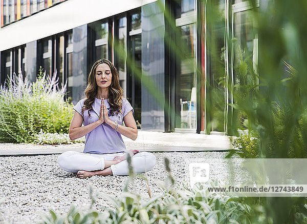 Woman practicing yoga in garden outsde office building