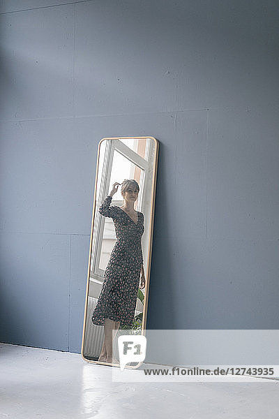 Young woman in vintage dress looking into mirror