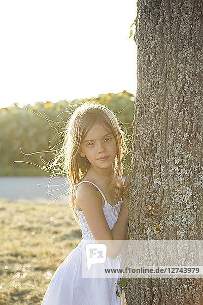 Girl standing on tree trunk at summer evening