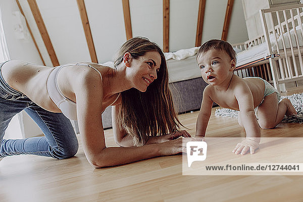 mother and baby son playing and crawling on floor