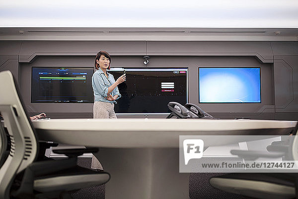 Businesswoman standing in front of monitor in futuristic office