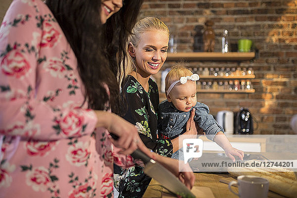 Female friends with baby girl preparing dinner together