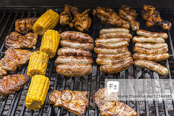 Different meat  maize and fried sausages on barbecue grill