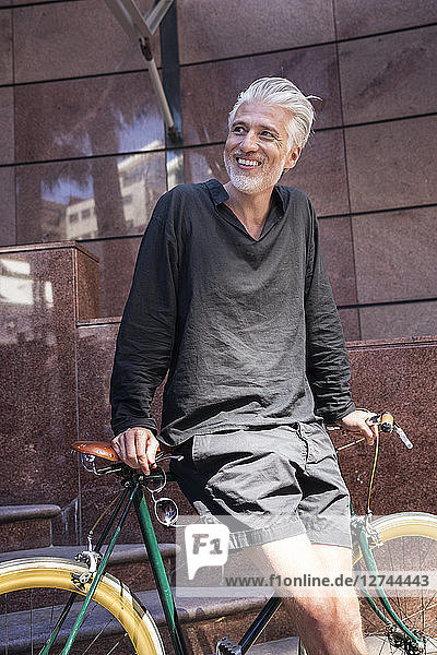 Mature man in the city leaning on his bicycle