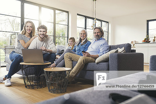 Extended family sitting on couch  using mobile devices