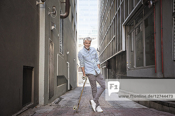 Mature man with longboard in an alley