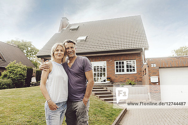 Portrait of smiling mature couple standing in front of their home