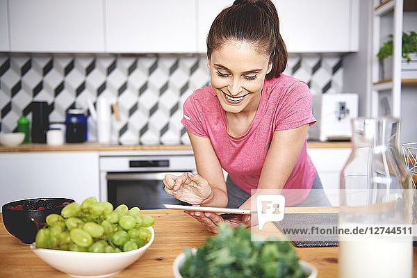 Smiling young woman using tablet in the kitchen