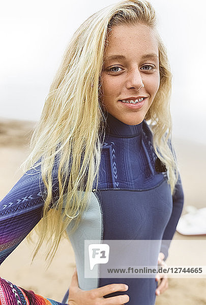 Spain  Aviles  portrait of smiling teenage girl in wetsuit on the beach