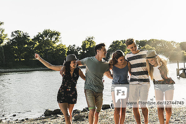 Group of happy friends arm in arm at the riverside