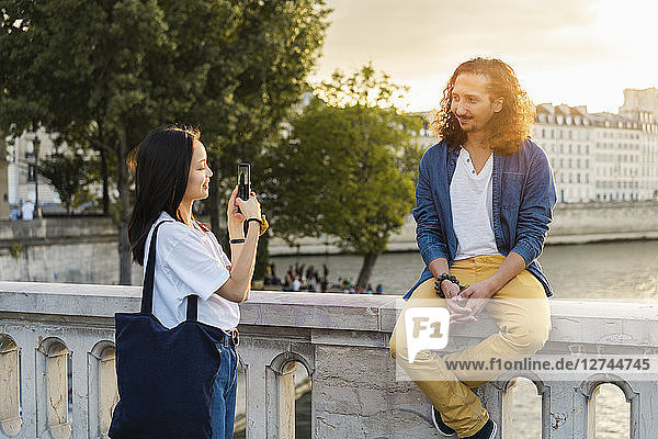 France  Paris  young woman taking a picture of her boyfriend at river Seine at sunset