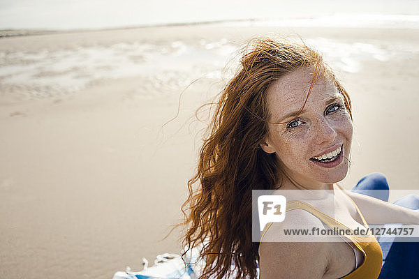 Portrait of a redheaded woman  laughing happily on the beach
