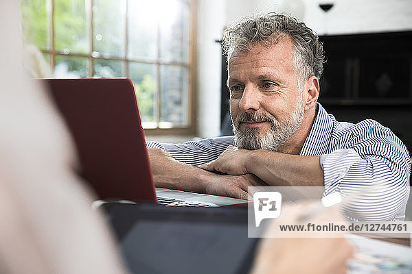 Mature man using laptop  woman holding digital tablet