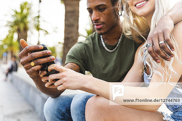 Hands of multicultural young couple holding smartphone