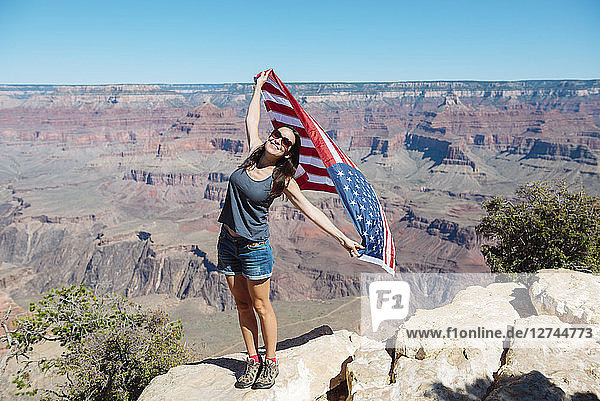 USA  Arizona  smiling woman with American flag at Grand Canyon National Park