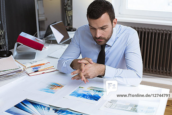 Businessman at desk in office looking at printouts