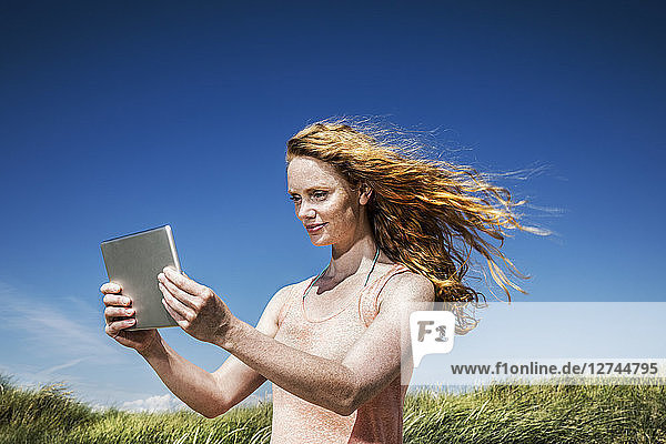 Netherlands  Zandvoort  woman standing in dunes with tablet
