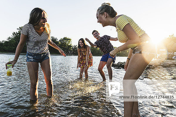 Group of happy friends having fun in a river at sunset