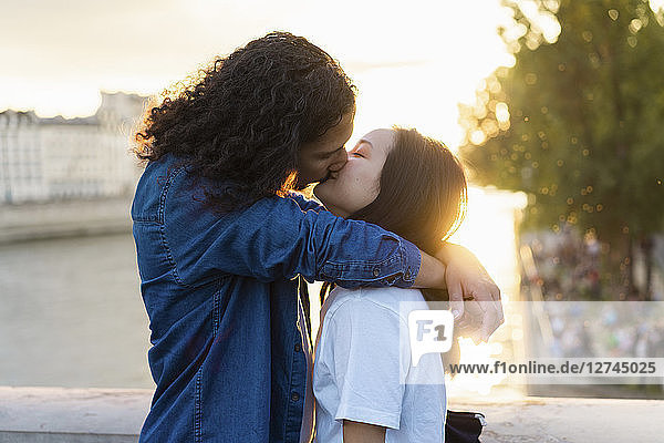 France  Paris  affectionate young couple kissing at river Seine at sunset