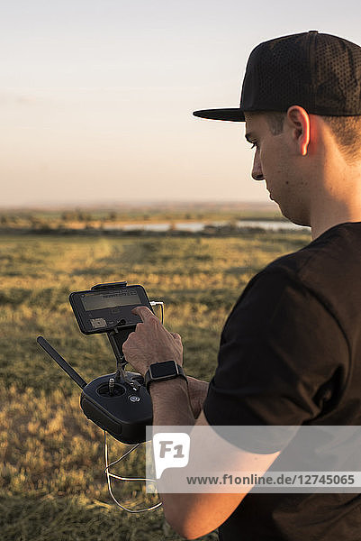 Man holding remote control for a drone in a field