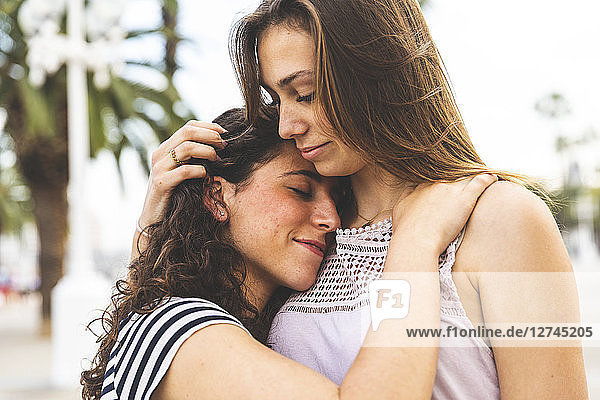 Two female friends embracing and hugging outdoors