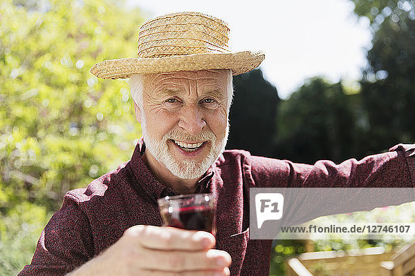 Portrait confident senior man drinking red wine in garden