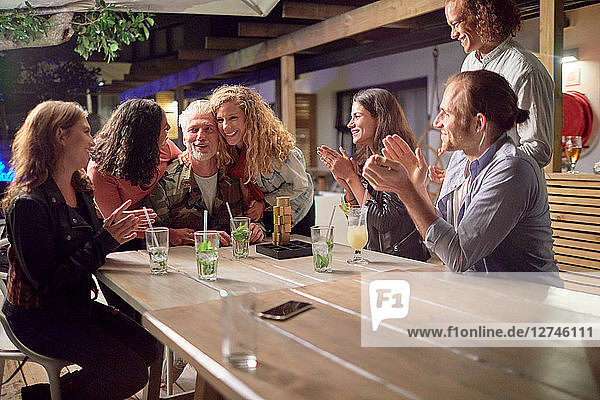 Happy friends clapping  celebrating on patio at night