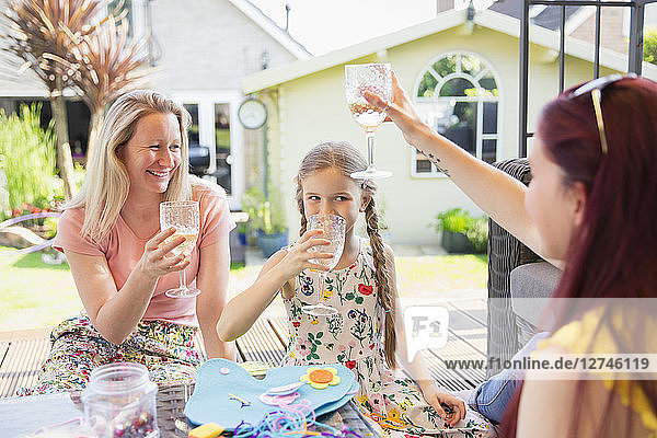 Lesbian couple and daughter drinking on sunny patio