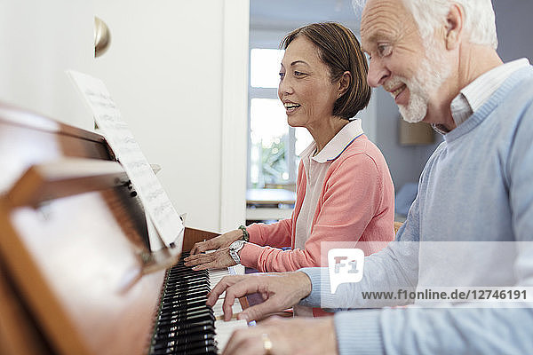 Active senior couple playing piano