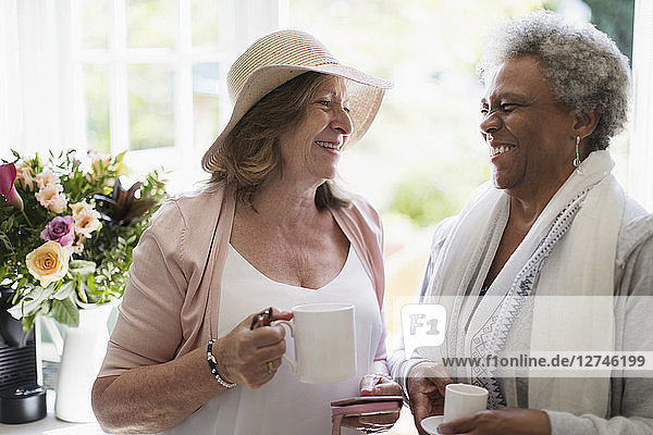 Happy senior women friends enjoying coffee