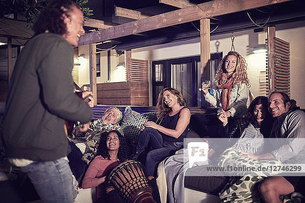 Happy friends hanging out  playing music on patio at night